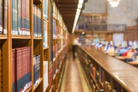 Pathway through library shelves, many books on each side.